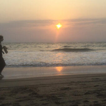 Une femme à la plage avec un coucher de soleil