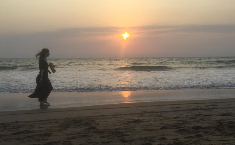 Une femme à la plage avec un coucher de soleil